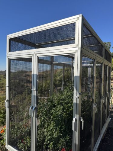 Heavy-duty garden enclosure built with EZTube aluminum square tubing and connectors, featuring a secure mesh frame and hinged access doors for ultimate plant protection.